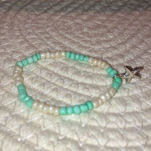 One white and blue bracelet with a silver starfish charm
